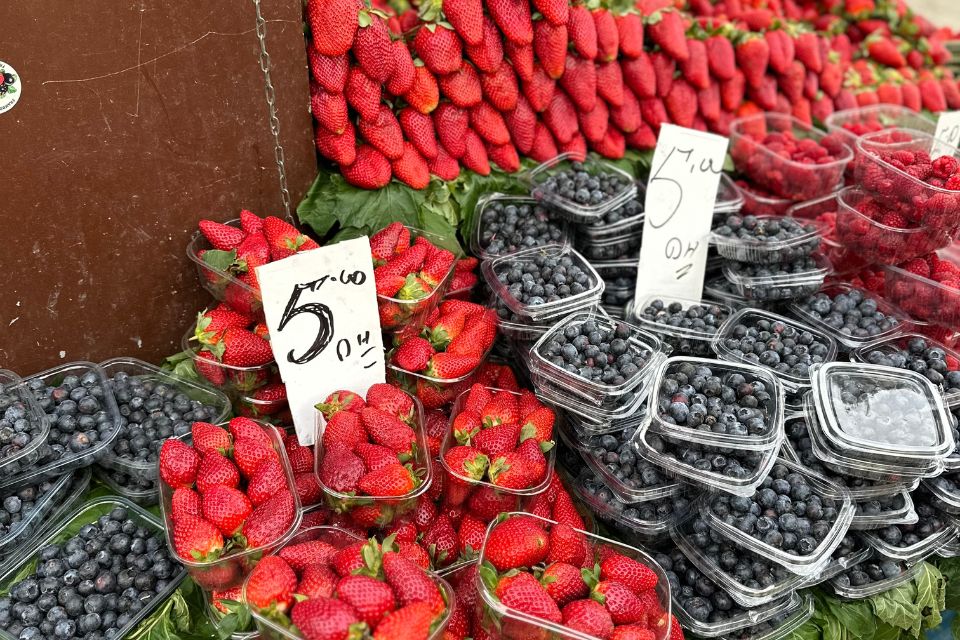 Rows of strawberries and blueberries for sale at a Tangier Food Tour market with price tags.