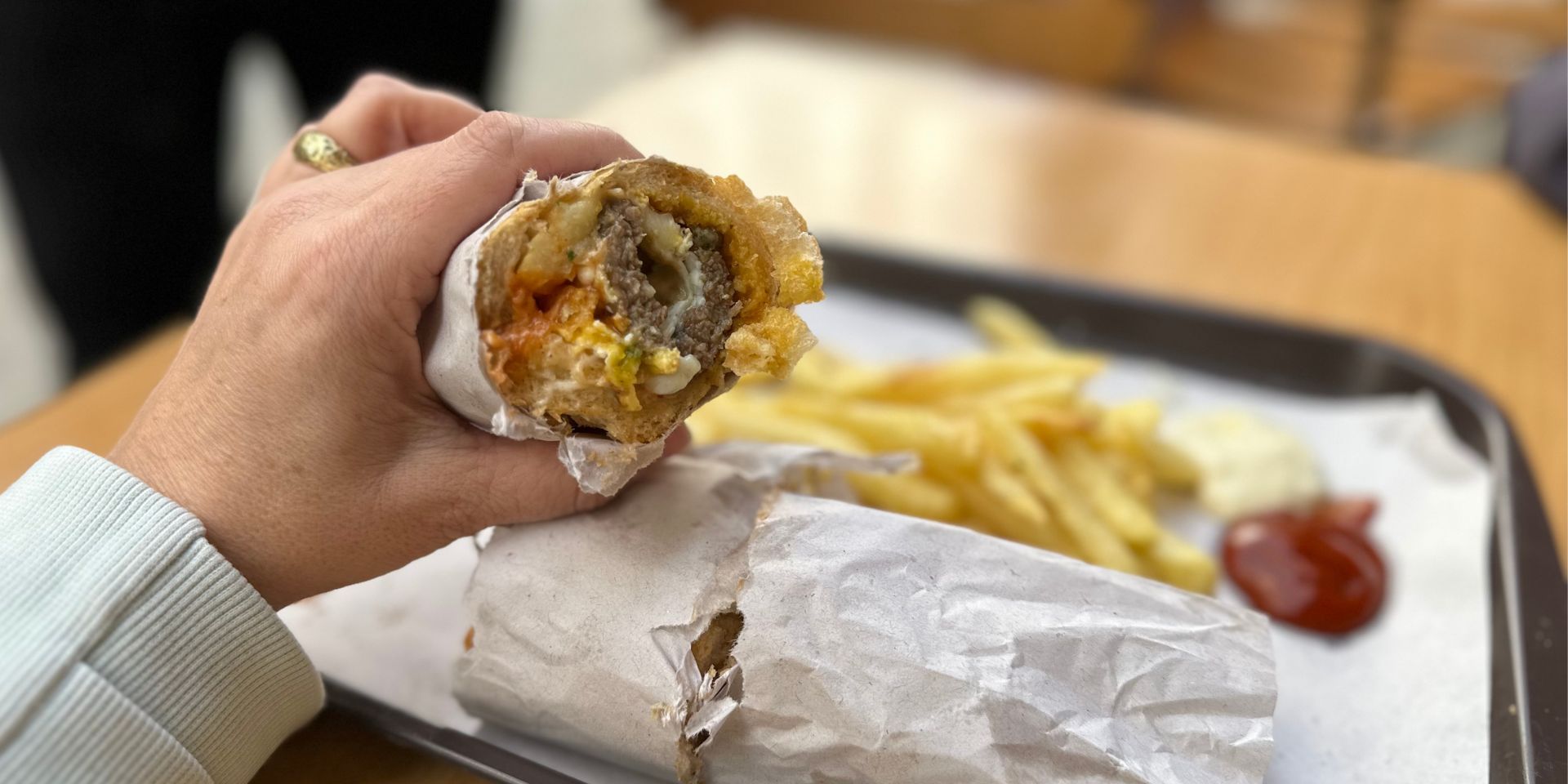 Close-up of a hand holding a half-eaten wrap with fries on a tray during a Tangier food tour.